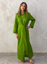 Vestido camisero largo color verde lima, con cuello camisero, mangas largas con puños abotonados, cierre frontal con botones y lazo anudado en la cintura.