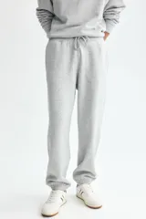 Pantalon deportivo de felpa gris claro melange, de corte relajado, con cintura elastizada y cordon de ajuste, bolsillos laterales y punos acanalados.