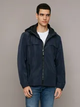 Campera ligera Calvin Klein de corte regular, confeccionada en tejido técnico resistente al viento. Presenta capucha con cordones ajustables, cierre frontal con cremallera, bolsillos laterales con cierre y puños elásticos.
