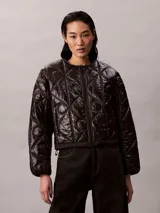 Campera acolchada Calvin Klein de color negro, con diseño matelasseado con monogramas, cuello redondo y cierre frontal de cremallera.