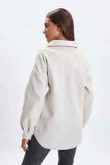Sobrecamisa de paño en color beige, con cuello camisero, cierre frontal de botones y dos bolsillos delanteros con solapa. Presenta un corte holgado y mangas largas.