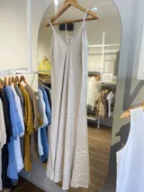 Vestido largo de lino color beige claro, con escote en V y tirantes finos dobles. El vestido tiene un corte recto y holgado.