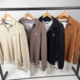 Sweater de punto negro con cuello polo, cierre de cremallera metálica y logo bordado en el pecho.