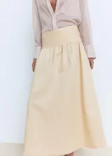 Falda midi evasé de tiro medio en color beige, con cintura entallada y bajo deshilachado.