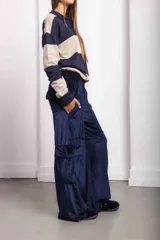 Pantalón cargo de terciopelo verde oscuro, de corte holgado, cintura elástica y bolsillos con solapa en la parte trasera. Cuenta con detalle de bordado rojo en la parte superior.