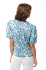 Blusa celeste con estampado de flores blancas, mangas cortas abullonadas y cuello redondo.