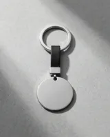Llavero circular de acero inoxidable con acabado pulido y correa de cuero sintético negro. Cuenta con una argolla metálica resistente para llaves.