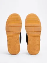 Zapatillas Tommy Jeans de corte bajo, color negro, con exterior de ante, interior de poliéster y suela de goma color caramelo. Presentan un panel a contraste en el talón, logo de Tommy Jeans en la lengüeta y etiqueta de la marca en el lateral.