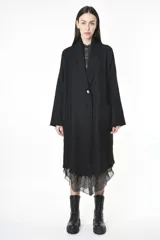 Tapado negro de paño con corte oversized, abotonadura simple y detalle de gasa en el ruedo.