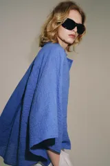 Camisa de mezcla de algodón de corte oversize y diseño asimétrico en tono azul, con cuello solapa, mangas tipo kimono por debajo del codo y cierre lateral con botones.