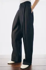 Jeans de tiro alto con corte balloon y largo completo. Presentan cintura con trabillas, bolsillos laterales ocultos, pinzas en el delantero y pespuntes marcados a contraste. Cierre frontal con cremallera, botón y ganchos metálicos.