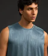 Musculosa deportiva masculina color beige, con cuello redondo y estampado sutil de líneas. Presenta recortes en los hombros y está confeccionada con tecnología Dry para mayor transpirabilidad.