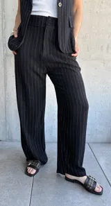 Pantalón negro de vestir con finas rayas verticales blancas, corte recto y tiro alto.