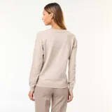 Sweater de punto fino en color beige, con escote en pico, manga larga y puños acanalados.