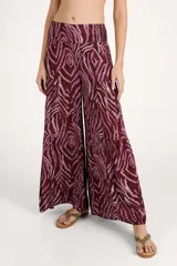 Pantalón de corte amplio con diseño de capas y cintura elástica con lazo frontal ajustable. Presenta un estampado animal print en tonos bordó y rosado.