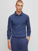 Remera polo de manga larga azul de algodón, corte slim fit, con cuello clásico y tapeta de dos botones. Incluye un pequeño bolsillo cuadrado en el pecho con el logo de la marca. 