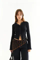 Top de manga larga confeccionado en tejido de lycra acanalada, color negro, con cierre frontal mediante botones metálicos a presión y detalle de botones en los puños.