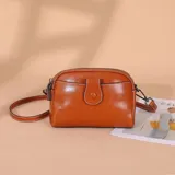 Cartera bandolera color tostado de diseño estructurado, con doble compartimiento con cierre, bolsillo frontal con solapa y tira ajustable desmontable.