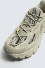 Zapatilla deportiva de estilo running, completamente negra, con capellada de malla y superposiciones sintéticas. Presenta una suela gruesa y voluminosa con diseño segmentado.