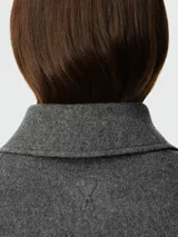 Chaqueta de corte boxy confeccionada en lana gris, con cuello clásico, cierre frontal de botones a tono y diseño minimalista.