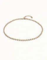 Collar de cadena formado por esferas continuas, con cierre de mosquetón y cadena de extensión. Está fabricado en una aleación de metales con baño de oro de 18k.