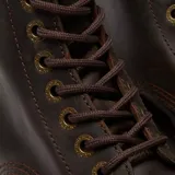 Botas de plataforma Dr. Martens modelo Sinclair, confeccionadas en cuero Crazy Horse color marrón oscuro con acabado desgastado. Presentan suela de goma estriada con costuras amarillas características, cierre frontal con cordones y cremallera central removible.