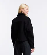 Campera corta negra de polivelour con cuello inglés, manga larga, cierre abotonado, bolsillos con solapa y botones en el pecho.