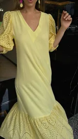 Vestido largo color amarillo pálido, con escote en V, mangas cortas abullonadas con detalle de calado y ruedo con volantes y calado.