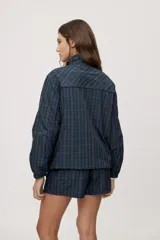 Campera liviana de calce relajado con estampado a cuadros en tonos de azul y verde. Cuenta con cuello alto, cierre frontal y mangas largas.