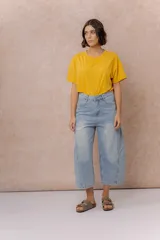 Pantalón de jean estilo barrel con tiro alto y pierna amplia de diseño curvo. Presenta un lavado celeste claro con efecto desgastado, cierre y botón frontal, y bolsillos funcionales.