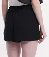 Short blanco de viscosa texturizada, modelo holgado con cintura de sastrería en el frente y elástico en la parte trasera. Presenta bolsillos laterales y cierre con botón y cremallera.