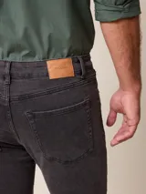 Pantalón de jean corte recto en color azul medio, con cierre de botón y cremallera, y bolsillos laterales y traseros.