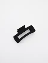 Pinza para el pelo color negro, de diseño rectangular con abertura central y acabado mate.