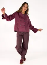 Chaqueta color tostado de corte recto y diseño cruzado con doble botonadura frontal. Presenta cuello solapa y mangas largas con puños acampanados y fruncidos.