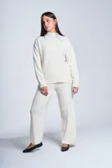 Sweater color beige de tejido de punto con cuello alto y mangas largas. Presenta detalles de ochos en diagonal en los laterales.