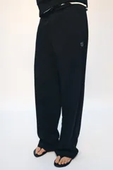 Pantalón tipo jogger de tiro medio con cintura elástica ajustable mediante cordones. Presenta un diseño de pierna recta, bolsillos laterales ocultos en las costuras y un detalle metálico con el logo ZA en la parte superior.