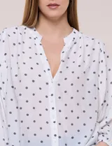 Blusa holgada de gasa texturizada color blanco con estampado de lunares negros, escote en V con botones frontales, mangas 3/4 abullonadas y puños elásticos.