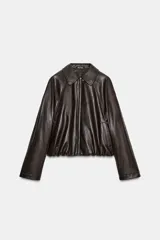 Chaqueta estilo bomber de efecto piel en color marrón oscuro, con cuello solapa, cierre frontal con cremallera, bolsillos delanteros de vivo y bajo acabado en elástico.