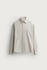Camisa relaxed fit de algodón con estructura, cuello solapa, manga larga con puño abotonado, bolsillo de parche en el pecho y cierre frontal con botones. Presenta diseño de rayas finas.