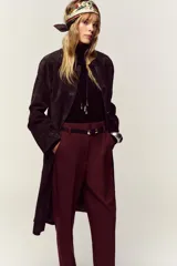 Pantalón de tiro alto y corte tobillero, confeccionado en tejido de aspecto denim oscuro. Presenta diseño de pinzas frontales, bolsillos laterales y cierre frontal con cremallera, botón y gancho. Incluye un cinturón fino a tono con hebilla metálica dorada.