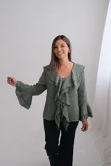 Blusa de lino color verde oliva con escote en V, volados frontales y mangas largas con puños acampanados de doble capa.