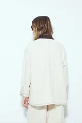 Sobrecamisa tipo Barn Jacket color marrón oscuro, de algodón con elastano, silueta relajada y estructura firme. Presenta cierre frontal con botones metálicos, cuello negro, bolsillos aplicados y pespuntes visibles.