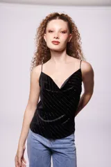 Top negro de terciopelo con breteles finos y escote en V. Presenta líneas verticales de lentejuelas plateadas.