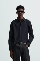 Camisa blanca de manga larga con cuello italiano y cierre frontal de botonadura. Corte regular fit.