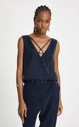 Blusa sin mangas color azul marino, con escote en V pronunciado, tirantes finos cruzados y detalle de argolla metálica central. Presenta un corte recto y caída ligera.
