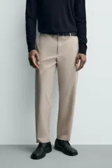 Pantalón de corte regular fit, color negro, confeccionado en tejido elástico. Presenta cintura elástica, cierre frontal con cremallera y botón, bolsillos laterales y bolsillos traseros de vivo.