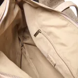 Cartera tipo tote de gran tamaño en color taupe, confeccionada en símil cuero con textura granulada. Presenta doble asa larga para llevar al hombro, cierre de cordones laterales y placa metálica frontal con logo grabado.