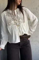 Camisa de lino color natural, con calce relajado, mangas largas amplias con puños fruncidos y delicado bordado geométrico en el frente.