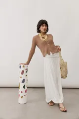 Falda larga blanca de tiro alto, confeccionada en tejido fluído con frunces en la cintura y diseño drapeado en el bajo.