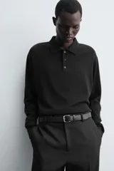 Cinturón de piel color negro con hebilla metálica plateada de forma rectangular y pasador a juego.